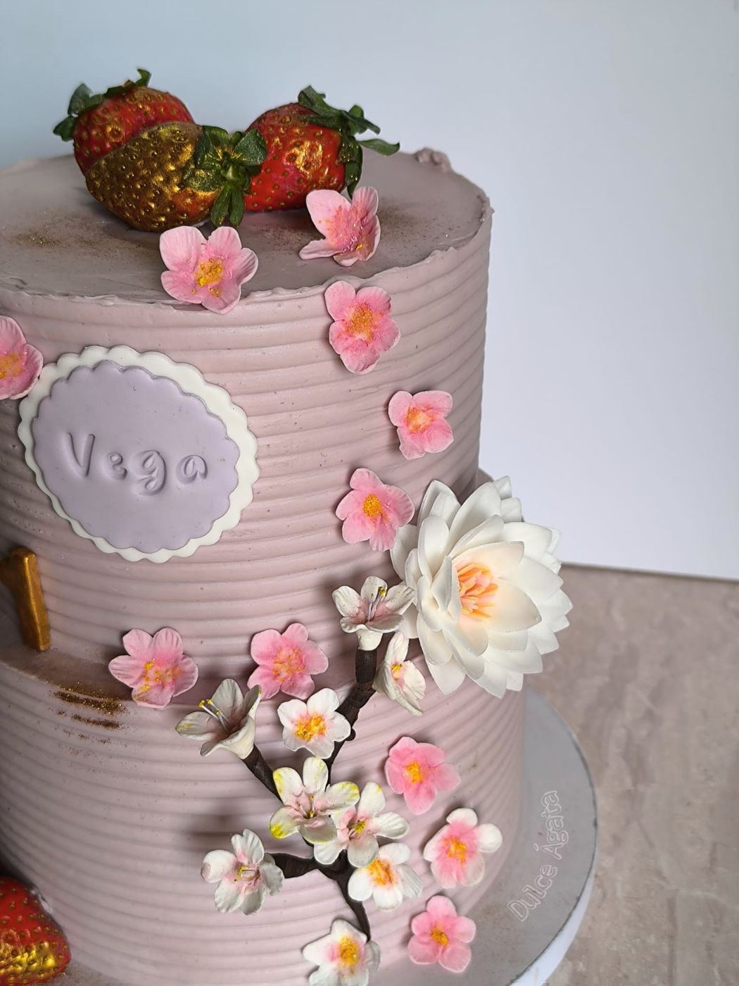 Tarta alta en tonos rosa con flores de azúcar y fresas